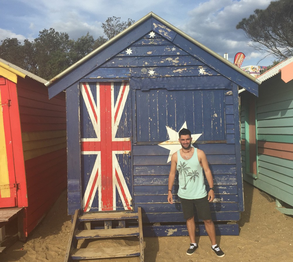 chico joven en una casita con la bandera australiana en la playa de Melbourne